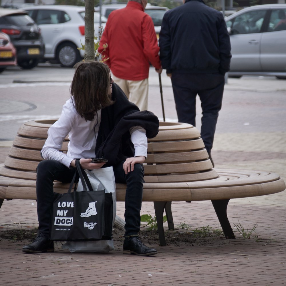 Alex Sutherland sitting on a bench and looking around