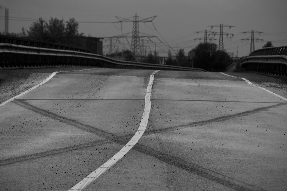 View back along the Zuiderlaaik from Twiske to Oostzaan. Bare road in foreground, blurred electricity pylons in background.