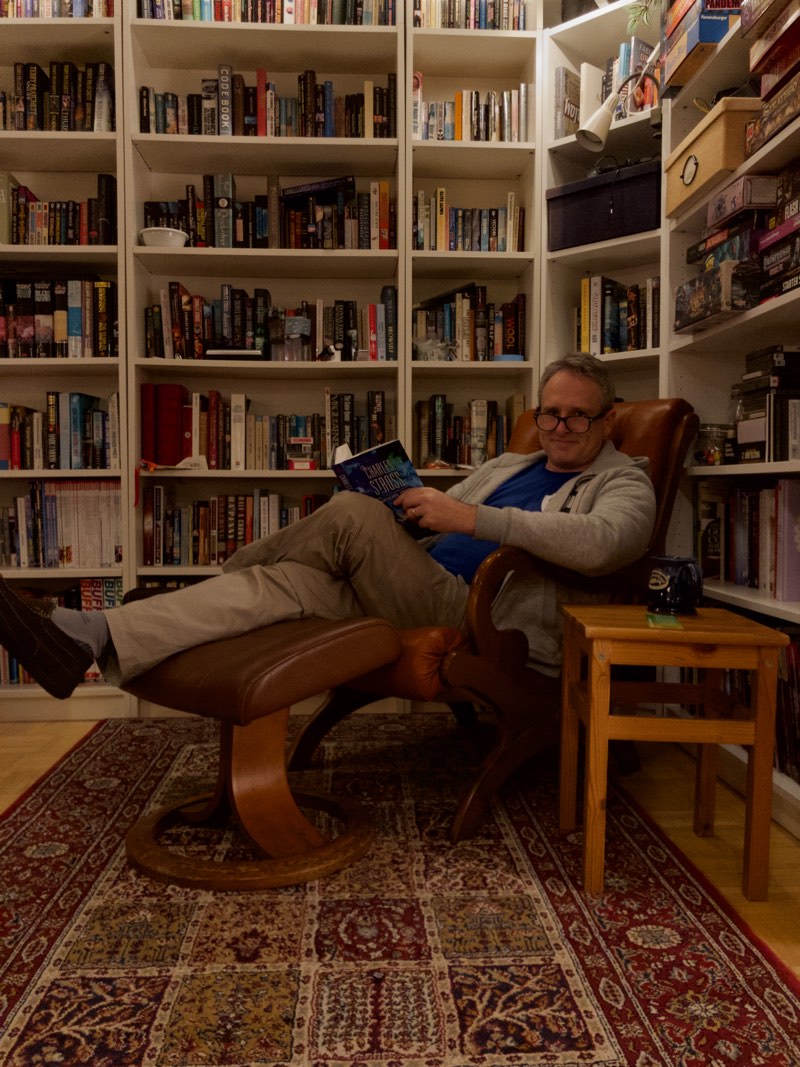 Martin Sutherland relaxing in his reading chair with the new Charles Stross book The Labyrinth Index